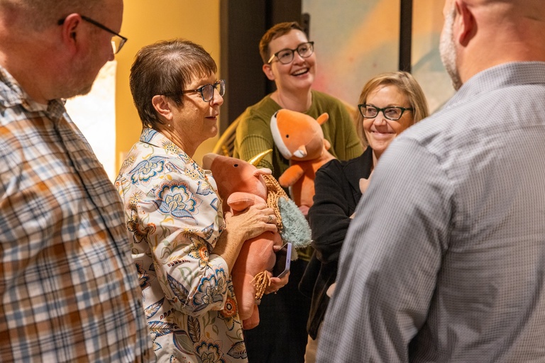 Pictures of staff holding weighted stuffed animals, talking and laughing